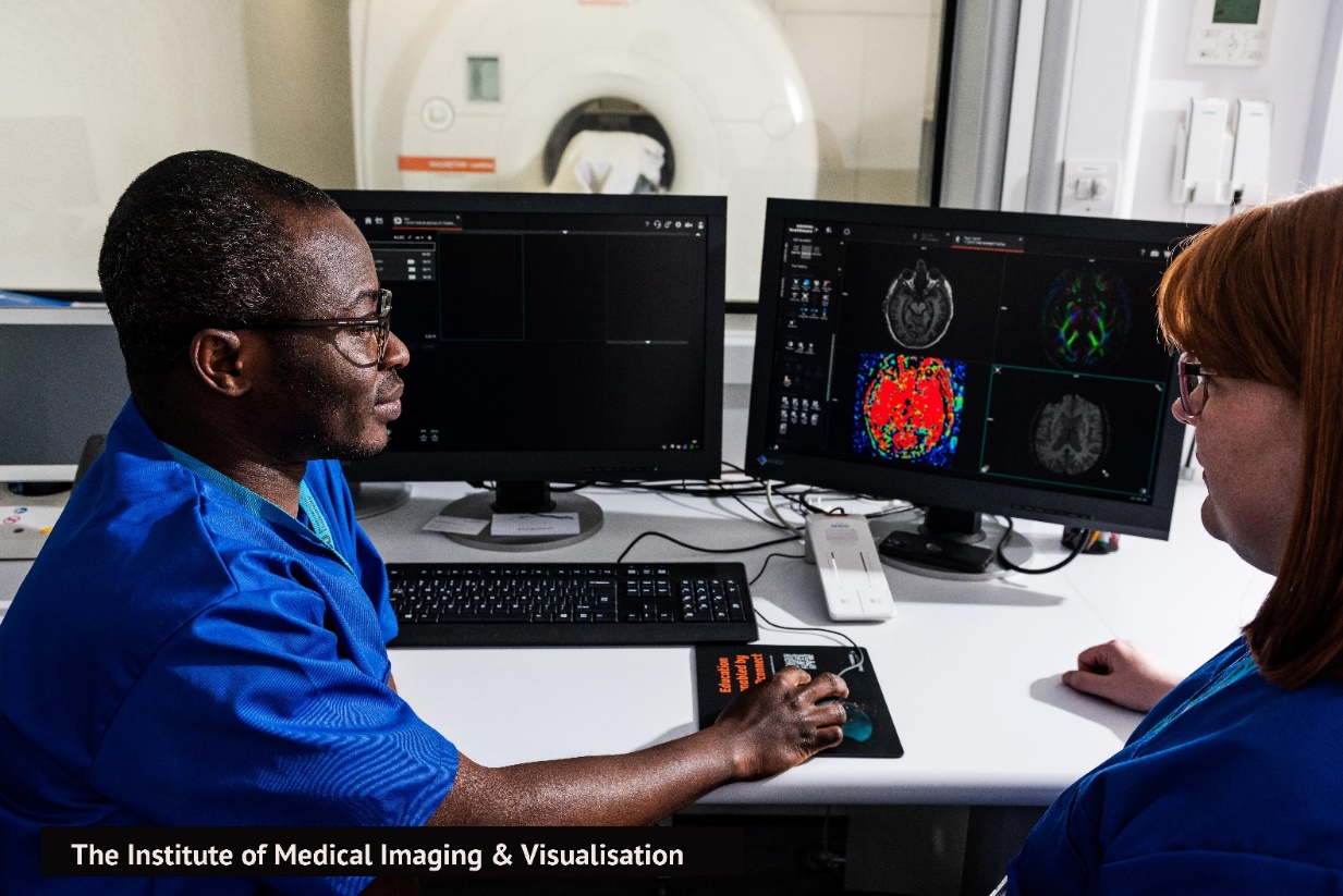 Staff at the Institute of Medical Imaging & Visualisation comparing scans in-front of the MRI scanner