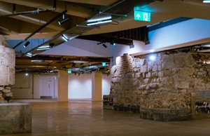 A large room showing stone remains of Roman undercroft converted to a new creative space.