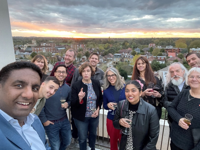 Creative Industries Network participants smiling and posing for a photo at sunset from the top of Town House with a view of Kingston in the background.