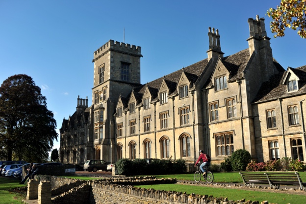 A person riding a bicycle in front of a large building Description automatically generated with medium confidence