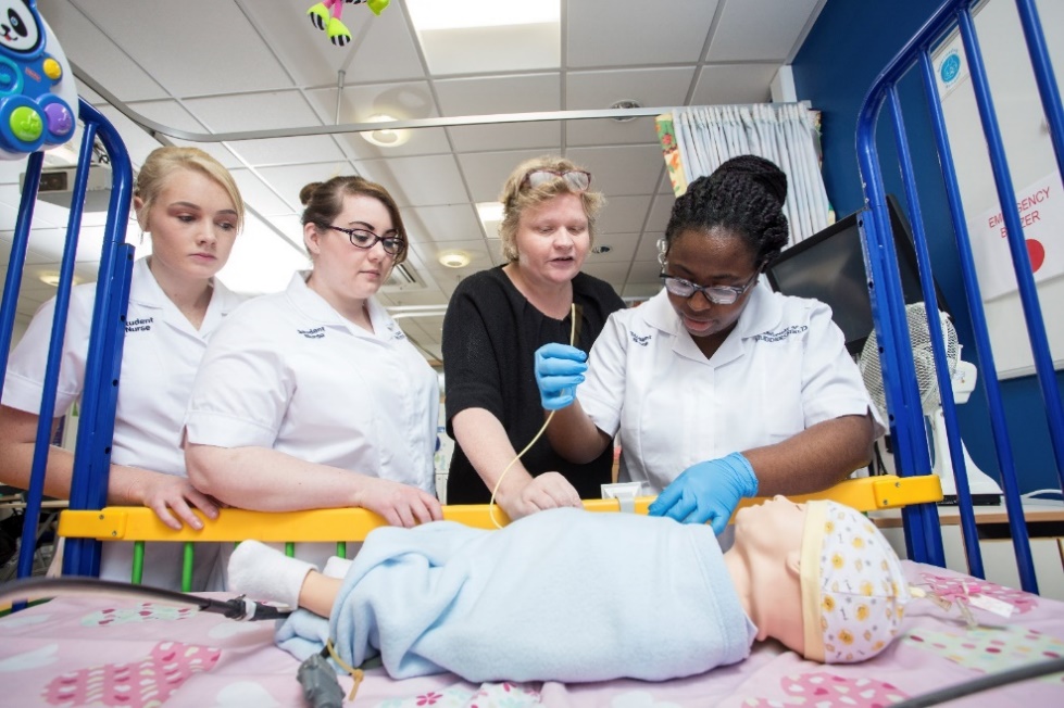 A group of three Nursing students learn with a lecturer in simulated clinical lab