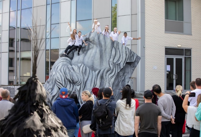 Picture of 'Stage Directions' event hosted at the University of Salford campus in Summer 2022. The photo shows students sitting on our Engels Beard installation outside of New Adelphi building.