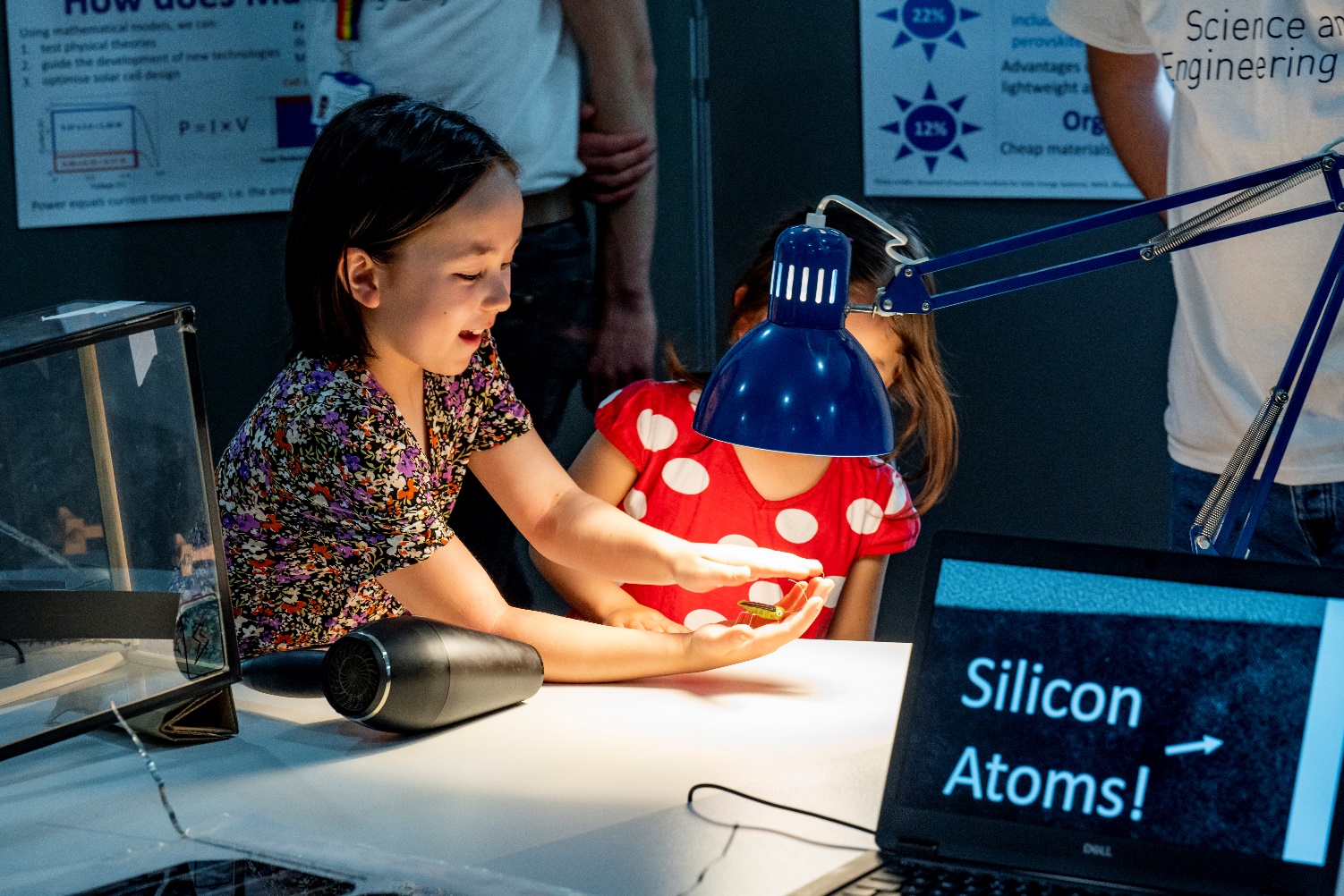 two girls exploring a science activity under a light Description automatically generated