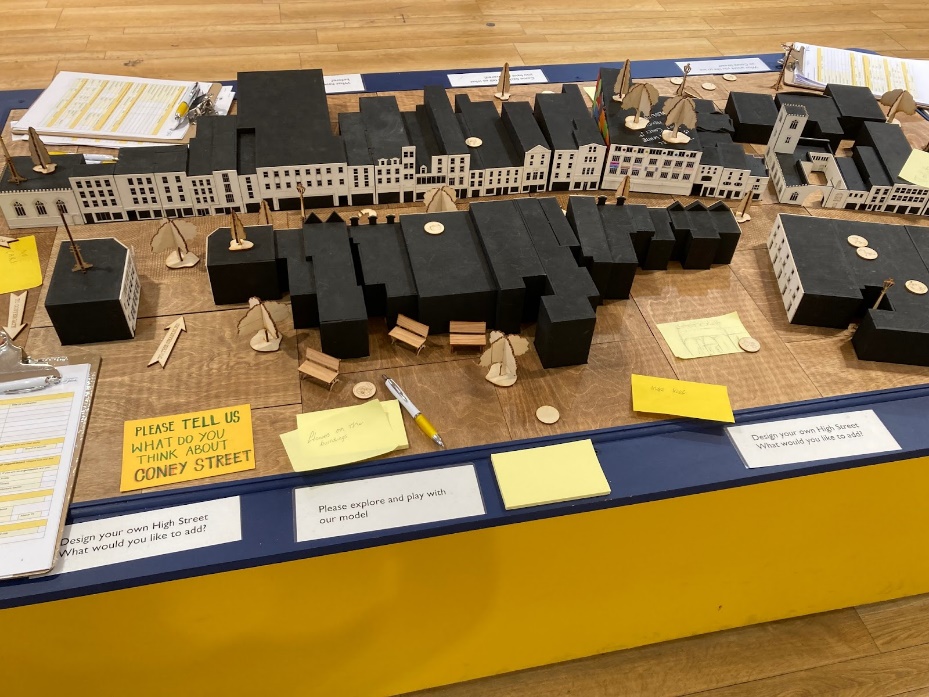 Physical model of Coney Street buildings on a table in the middle of the room, with requests for people to suggest future development for the high street.