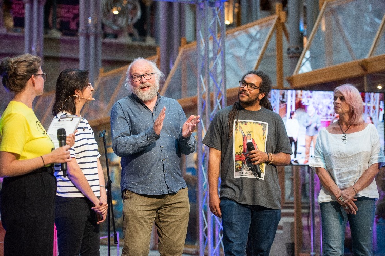 Five members of the community and researchers standing on a stage at the Oxford Museum of Natural History in conversation.