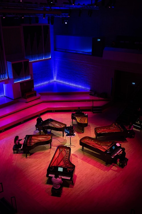 Performance of Eastman's 'Gay Guerrilla' for 6 pianos being performed in RNCM Concert Hall.