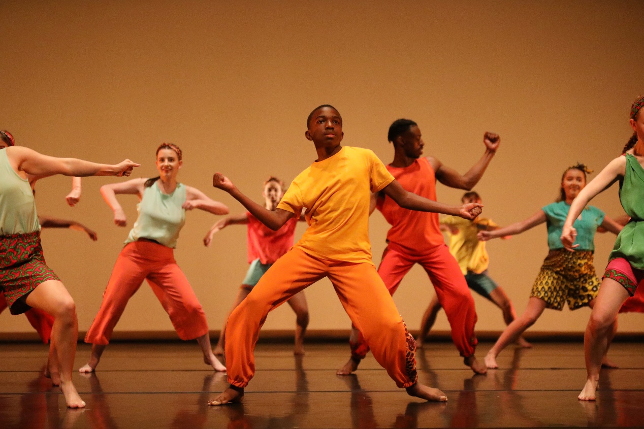 Picture of a group of children and young people dancing in bright coloured costumes